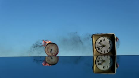 burning  two old  alarm clocks on mirror in space.