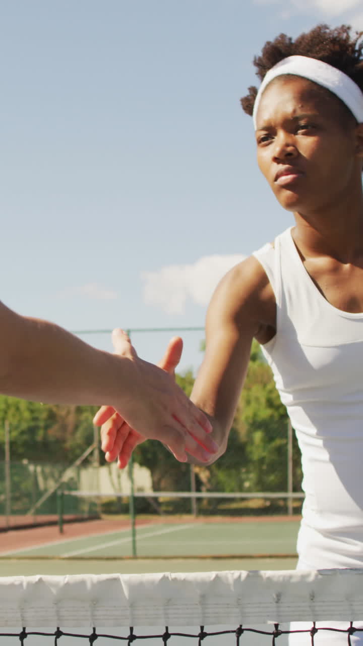 Video of african american female tennis player holding racket and shaking hand with friend