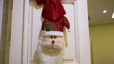 cute soft santa face hanging on white door as festive christmas decor