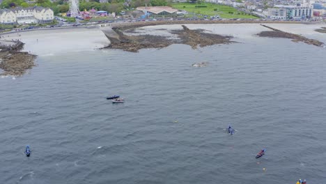 Aerial-orbit-tilt-up-of-currach-boats-in-water-off-coast-of-ladies-beach-galway-ireland