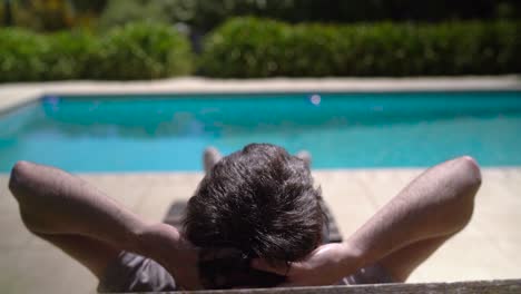 tipo acostado en una silla de descanso relajándose junto a la piscina