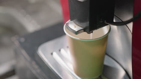 close-up of coffee machine dispensing hot coffee into cup, steam rising, with focus on precise pouring action and appliance in use in kitchen environment