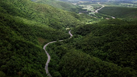 logistic concept aerial view of countryside road - motorway passing through the serene lush greenery and foliage tropical rain forest mountain landscape