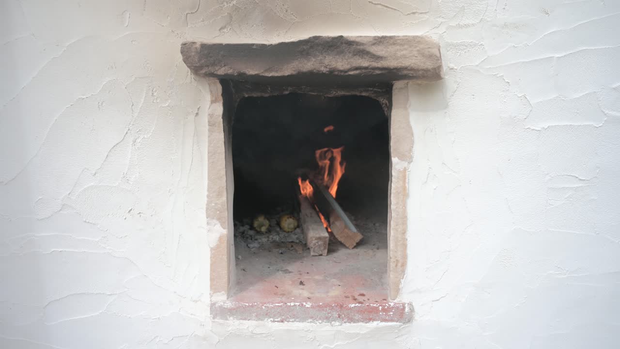 Frontal view of a traditional oven lit with fire cooking corn cobs