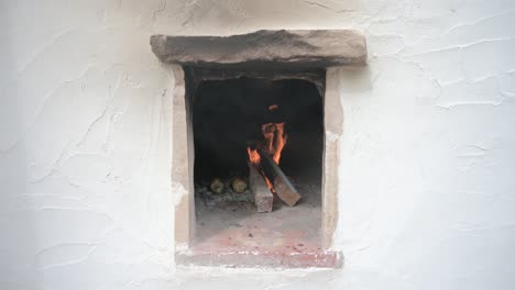 frontal view of a traditional oven lit with fire cooking corn cobs