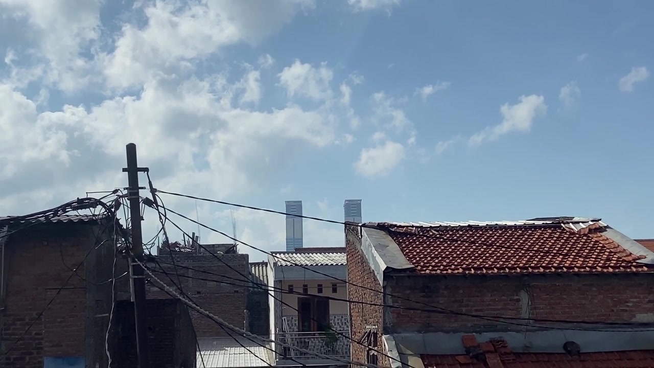 Tetti urbani con grattacieli in lontananza e cavi elettrici aggrovigliati