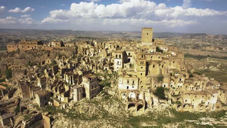 Drone-Volando-De-Lado-Con-La-Cámara-Inclinándose-Hacia-Abajo-Filmando-Lentamente-Las-Antiguas-Ruinas-De-Craco-En-Una-Colina-En-El-Sur-De-Italia-En-4k