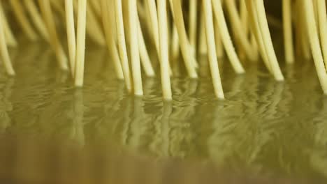 close up of boiling strings of spaetzle noodle in a factory in slow motion