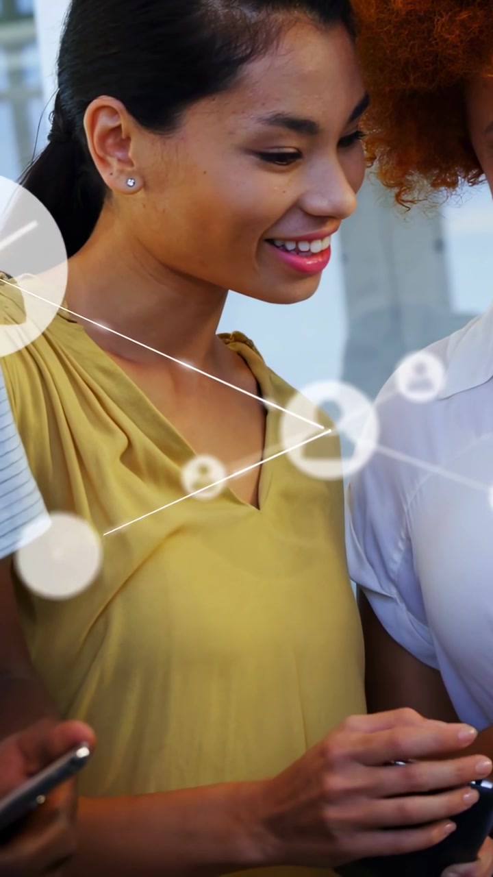 Vertical video: Lead woman tapping phone, causing network overlay growing across office for sharing