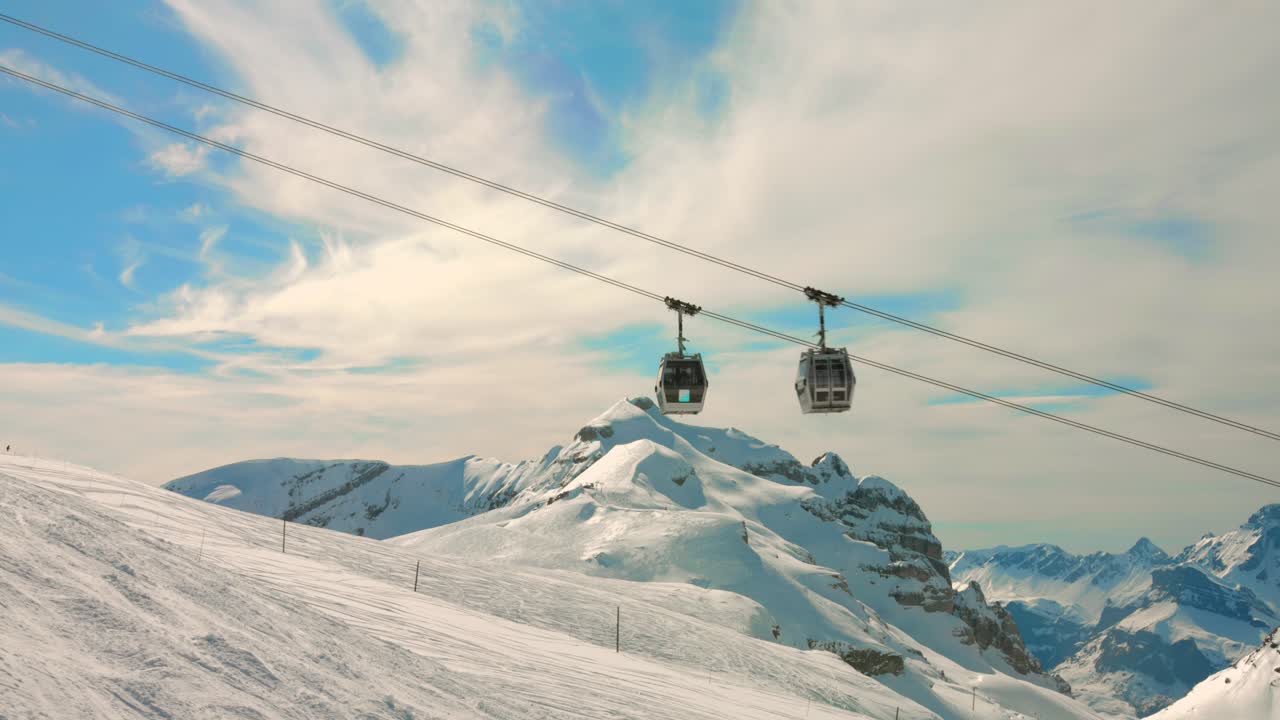 Vista di una seggiovia nelle Alpi francesi, con le montagne innevate sullo sfondo