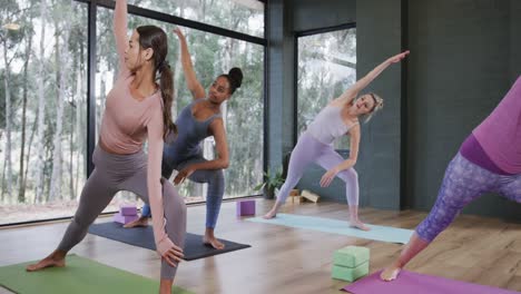 Focused-diverse-women-stretching-together-on-mats-in-yoga-class-with-female-coach,-slow-motion