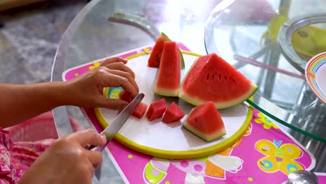 manos de persona cortan deliciosa sandía roja en trozos pequeños