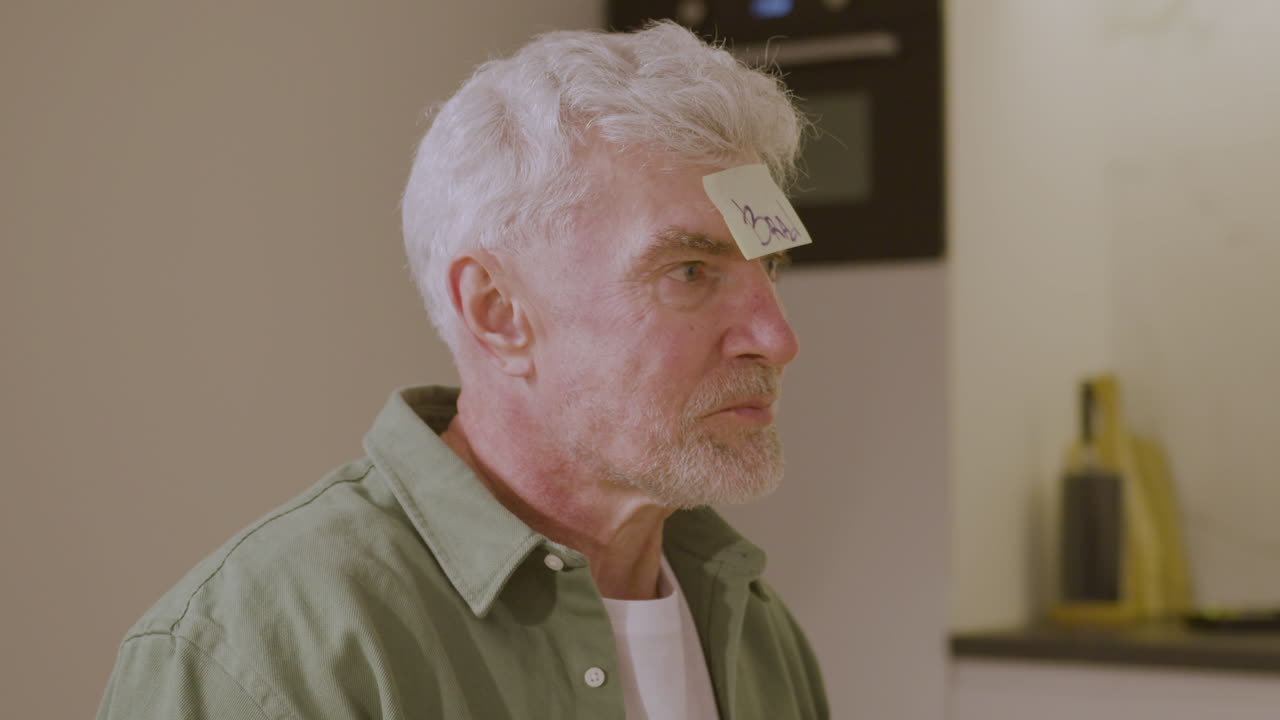 이마에 부착된 끈적끈적한 종이로 게임을 하는 행복한 노인