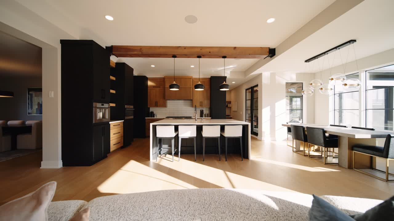A sleek, modern kitchen with an island, wooden cabinets, and pendant lighting, filled with natural light from large windows