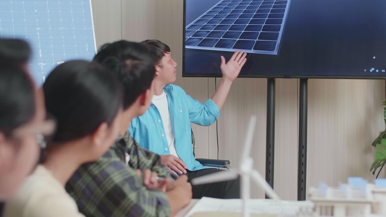 Asian Man Engineer In Wheelchair Presenting About The Work Of Solar Cell To His Colleagues At The Office