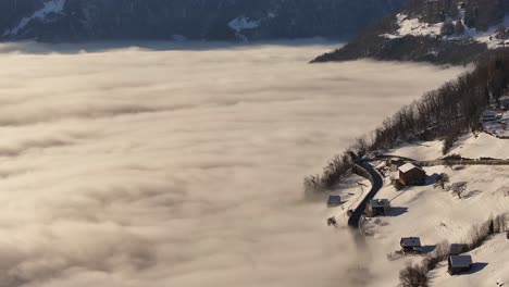 breathtaking aerial view of the village of amden in switzerland, blanketed by fog on a winter day in the swiss alps, creating a mystical alpine atmosphere.