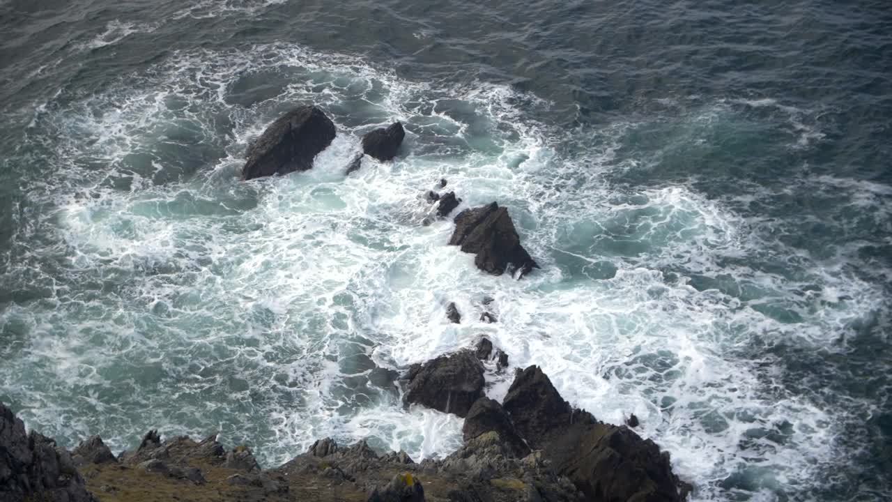 Onde che si infrangono sugli scogli viste da una scogliera lungo la costa dell'Irlanda.
