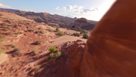 fpv drone diving and flying through the hidden red sandstone funnel arch in the sandy and rocky desert of moab utah