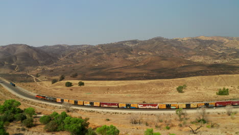 el tren rueda a lo largo de las vías debajo del sitio de un gran incendio forestal cerca de caliente, california - vista aérea