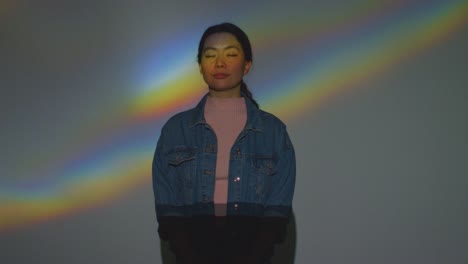 프리스마에서 무지개 패턴이 그녀의 얼굴에 투사되는 몰입 예술 전시회를 방문하는 여성