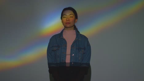 woman visiting immersive art exhibition with rainbow pattern from prism being projected onto her face