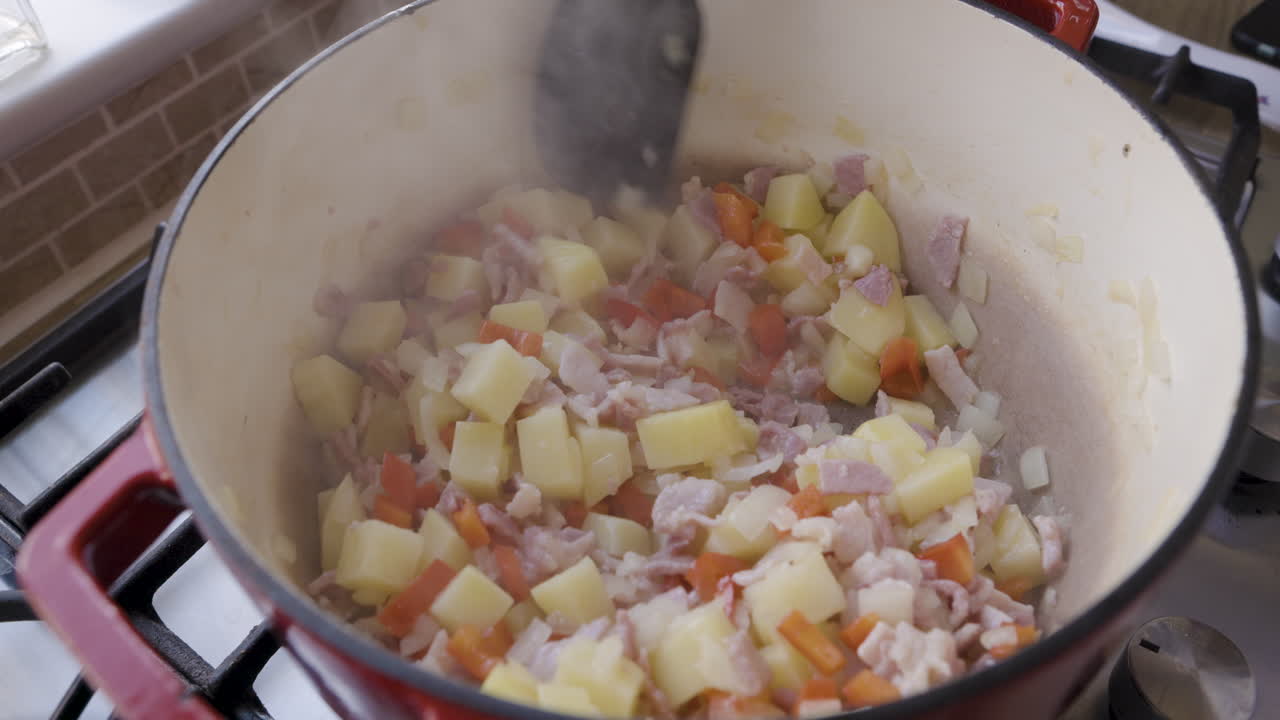 Cooking potatoes, ham, and red peppers in a dutch oven