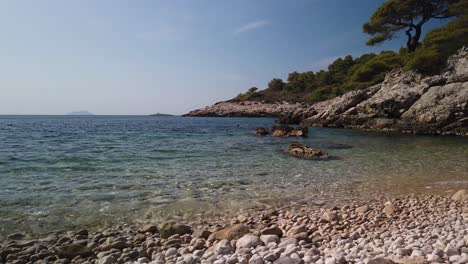 view of the pebbly barjoska beach on the island of vis in croatia with a lone snorkeler in the distance