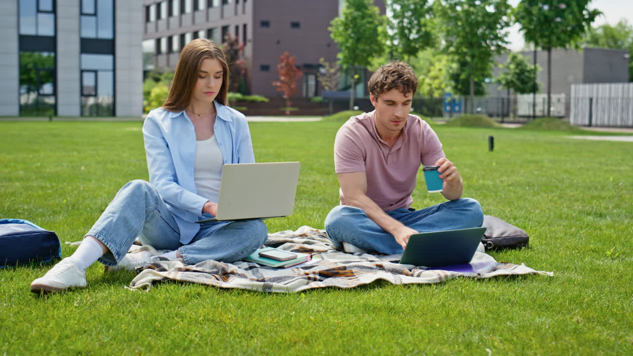 Man woman working park together looking laptops. Two students studying online