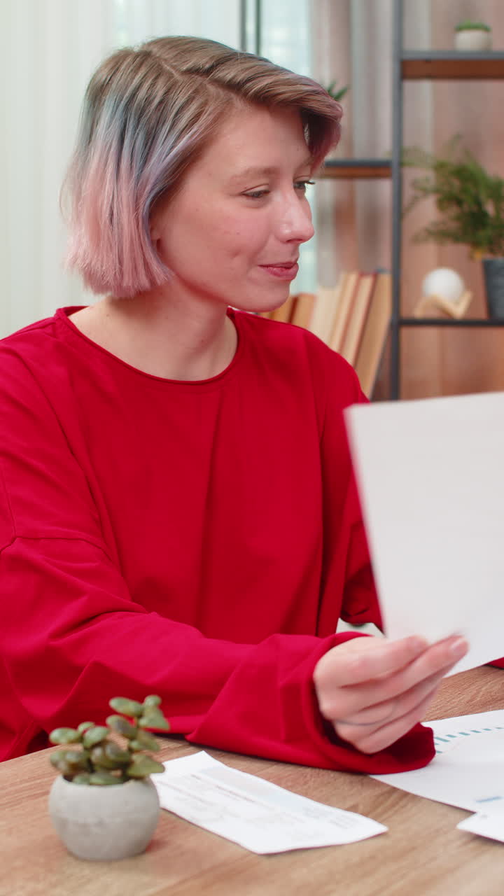 Young woman happily reviewing financial documents nodding positively satisfied successful results