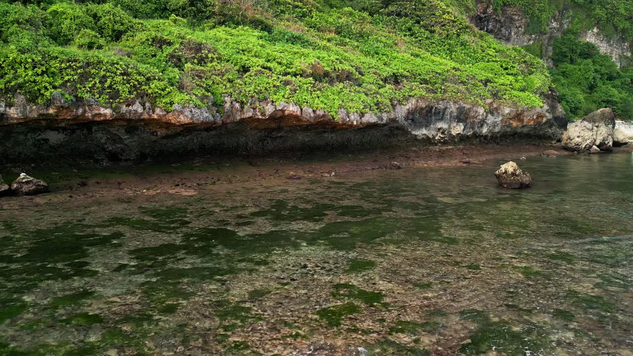 Scenic drone footage of Nyang Nyang Beach, Uluwatu, revealing limestone cliffs, shallow water, and untouched natural beauty of Bali’s secluded southern coastline