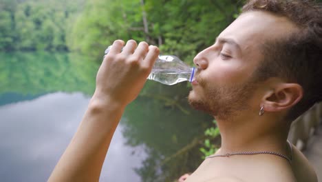 beber agua en la naturaleza, el hombre muscular está bebiendo agua.