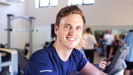 portrait of active man resting after exercising on cycling machines in gym