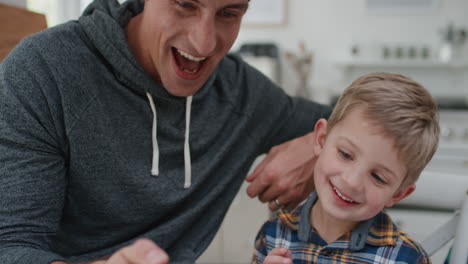 father and son using smartphone watching online entertainment on mobile phone happy little boy having fun relaxing with dad at home 4k footage