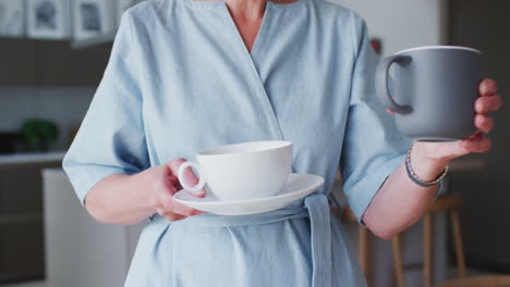 senior couple standing in kitchen and talking whilst drinking coffee