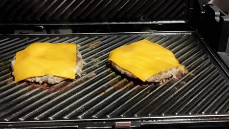 Zwei-Hausgemachte-Cheeseburger-Kochen-Auf-Einem-Schwarzen-Grill