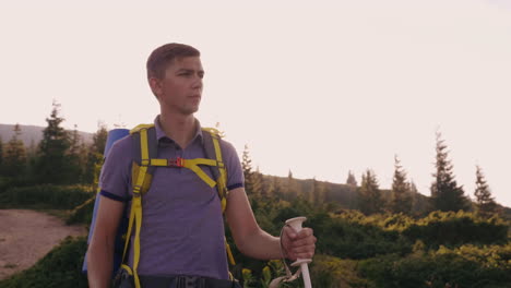 a young tourist rises up the mountain uses trekking sticks against the background of a picturesque s