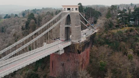 Backwards-tracking-shot-reveal-of-the-Clifton-suspension-bridge-from-right-to-left-over-the-River-Avon,-Bristol,-during-overcast-cloudy-day