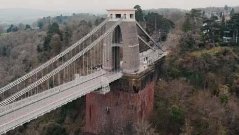Backwards tracking shot reveal of the Clifton suspension bridge from right to left over the River Avon, Bristol, during overcast cloudy day