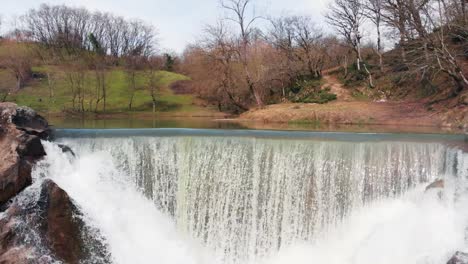Aerial drone footage of beautiful lake and waterfall in a forest during spring 2