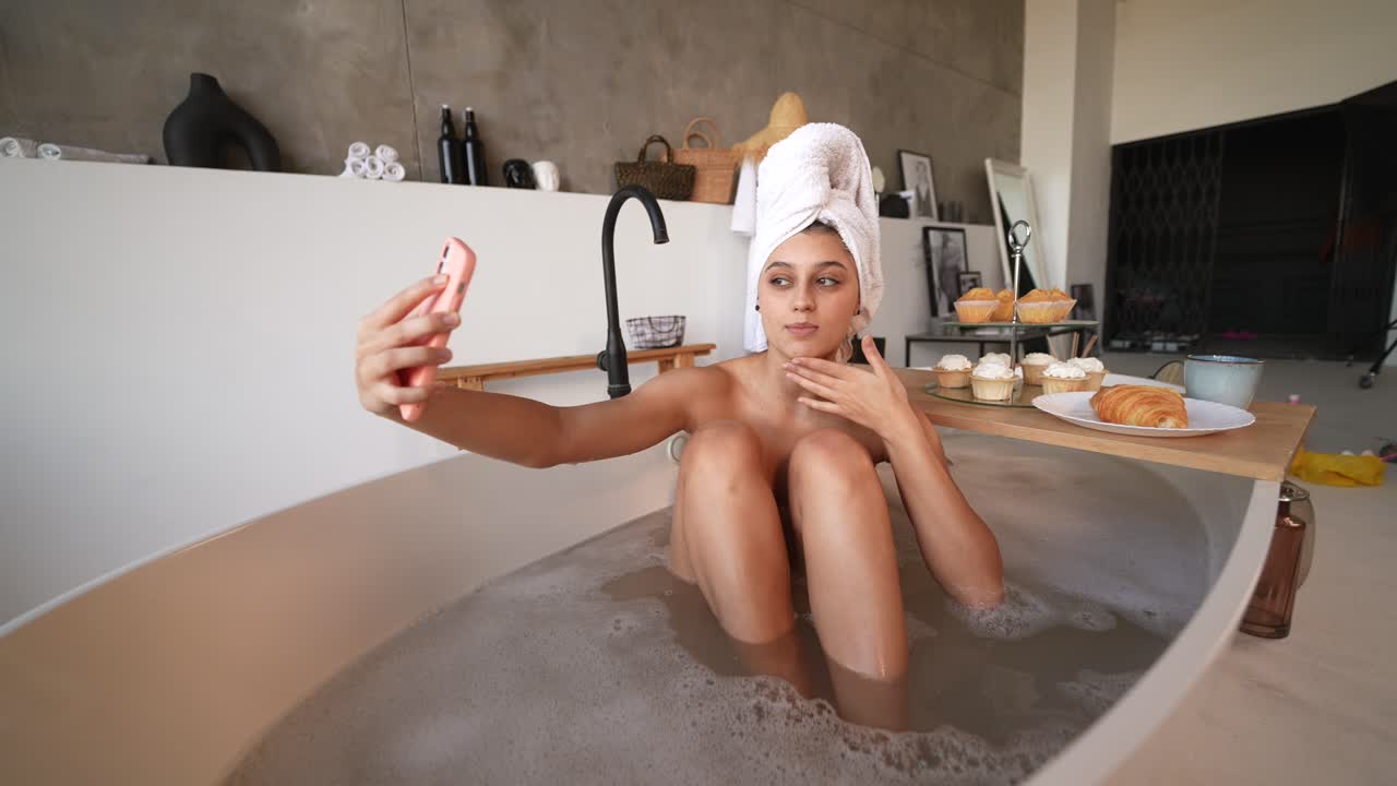Woman taking a selfie in a bathtub with pastries
