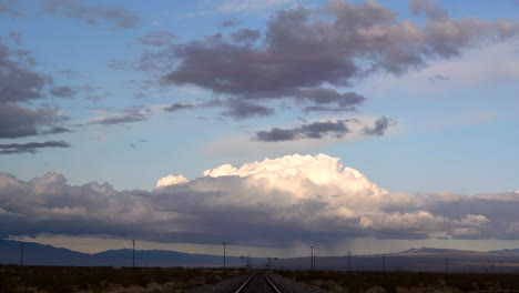 nubes de tormenta moradas recorren el cielo azul sobre las vías del tren en el desierto, lapso de tiempo