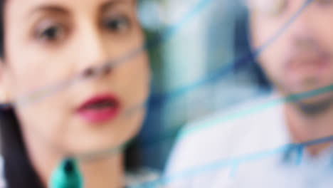 female engineer drawing graph on glass showing mathematical formula in creative university brainstorming ideas showing student working together sharing data  in modern glass laboratory