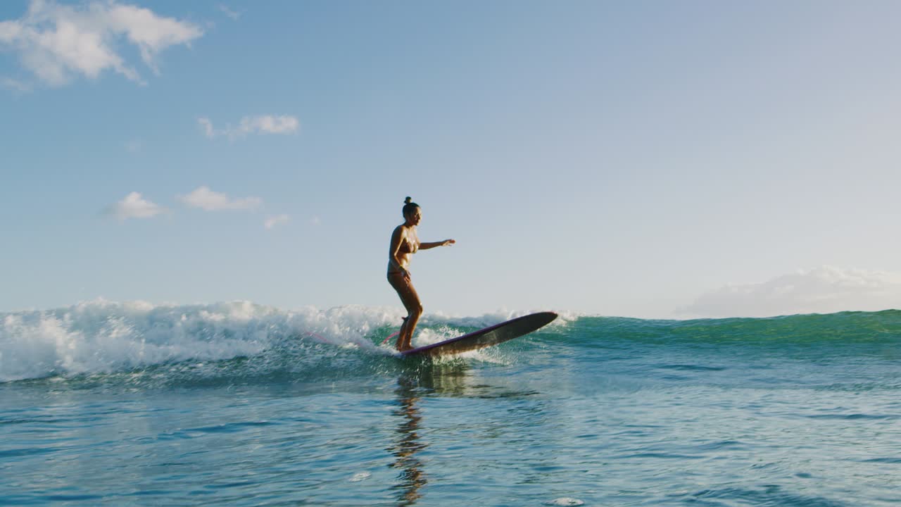 una mujer joven surfeando al atardecer.