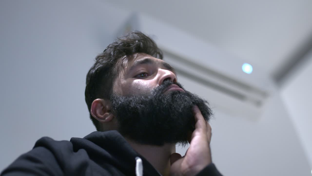 Un uomo annoiato guarda in basso e si sfrega il mento.
