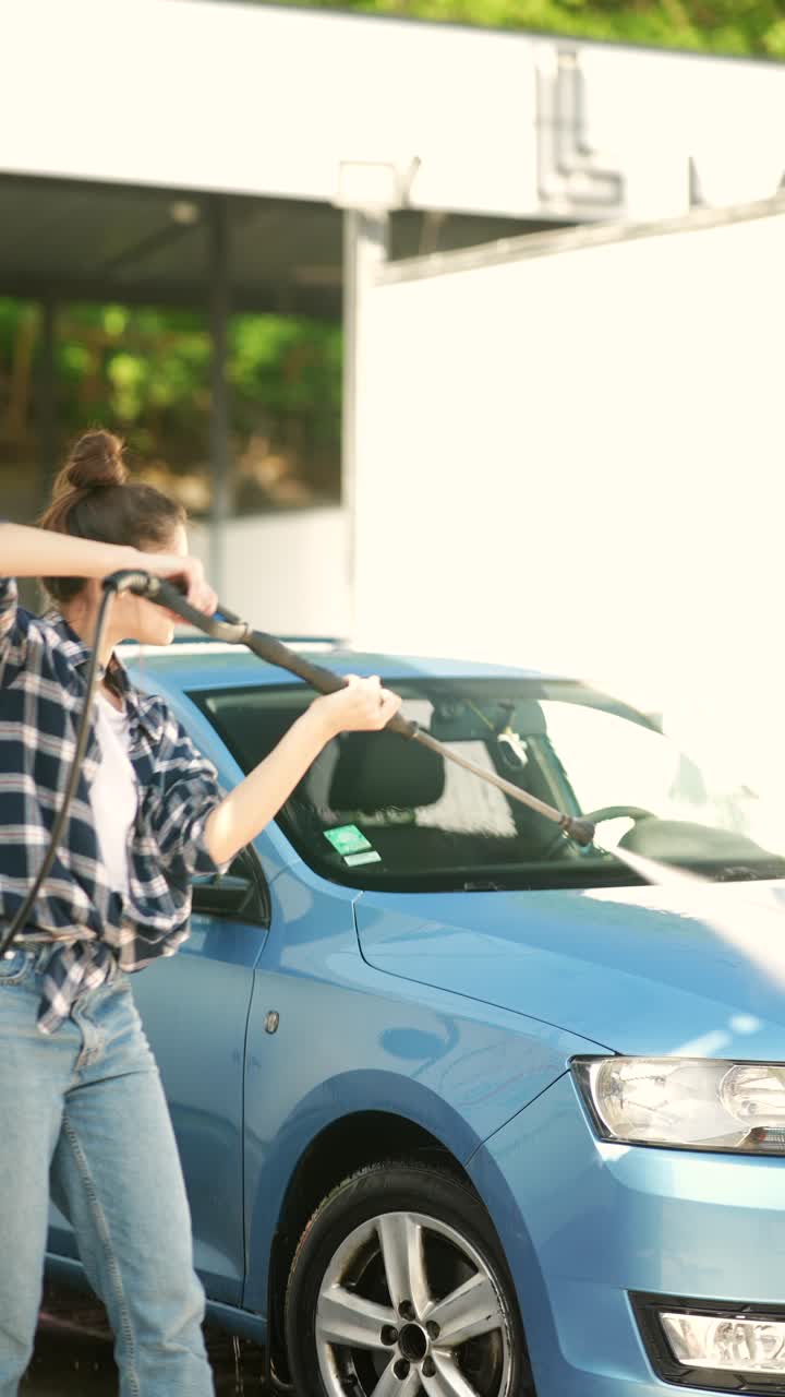 mujer lavando un coche azul en un lavado de coches de autoservicio