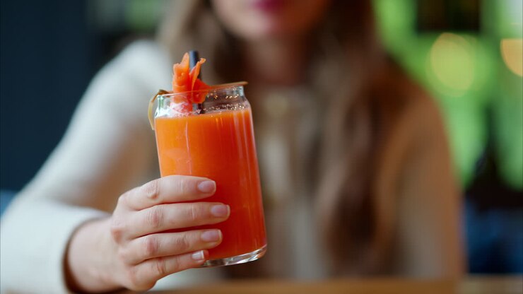 Donna che beve succo di carota con una cannuccia, in un ristorante