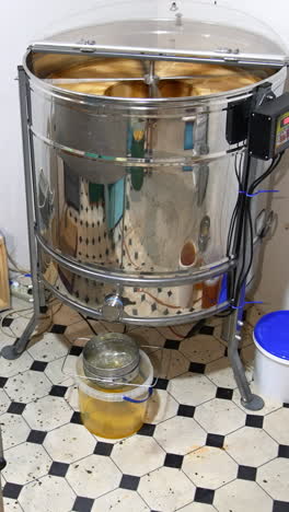 little room in the apiary for harvesting honey. electric machine extractor working in the corner. few buckets are filled with freshly removed honey. vertical video