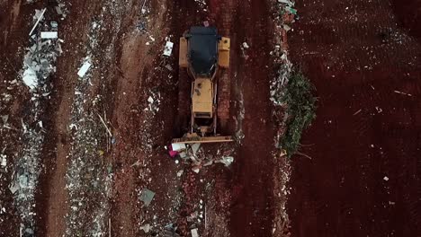 una topadora empuja basura en un vertedero - vista aérea hacia abajo