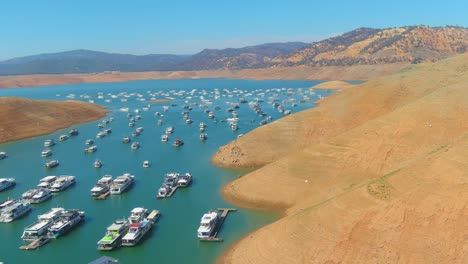 Increíble-Antena-Sobre-El-Lago-Oroville-De-California-Azotado-Por-La-Sequía-Con-Bajos-Niveles-De-Agua,-Costa-En-Retroceso-Y-Casas-Flotantes-Varadas