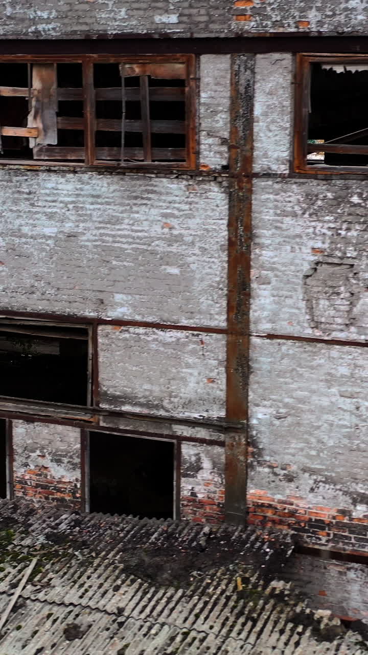 Damaged building with broken windows. Abandoned place after the war. Exterior of empty building during military actions. Vertical video